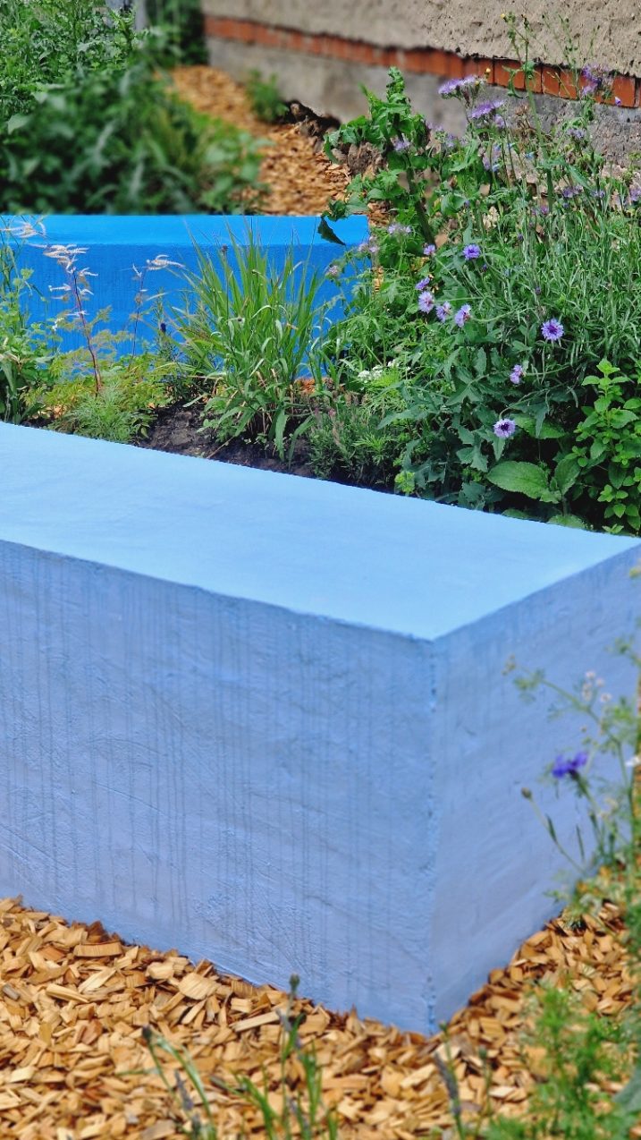 Stauden und Blumen vor einem blauen Betonblock – Natur- und Spielraum Kita Sternenwelt HIKITA.