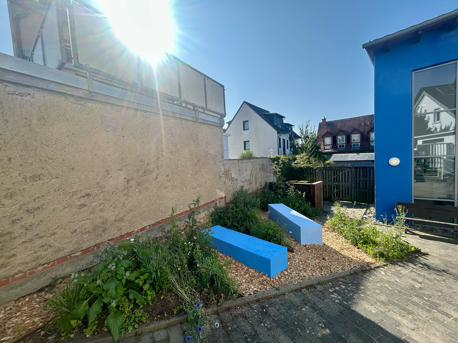 Außenraumgestaltung Kita Sternenwelt mit blauen Sitzblöcken und bepflanzten Flächen – Extrathings Landscape Studios.