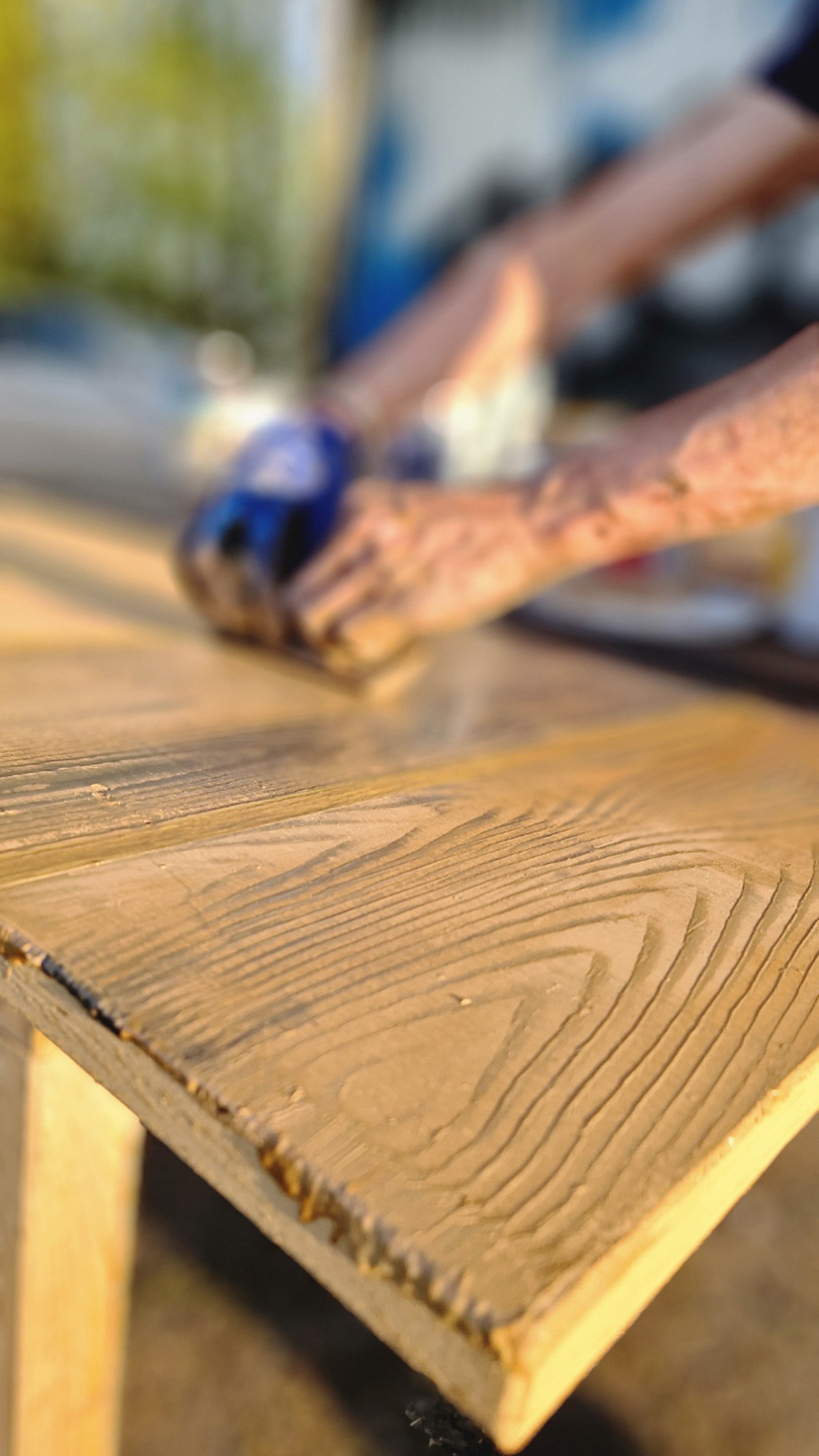 Handwerker schleift Holzplatte mit sichtbarer Maserung – Bühnenbau von Extrathings Landscape Studios für ‚Peter Pan‘.