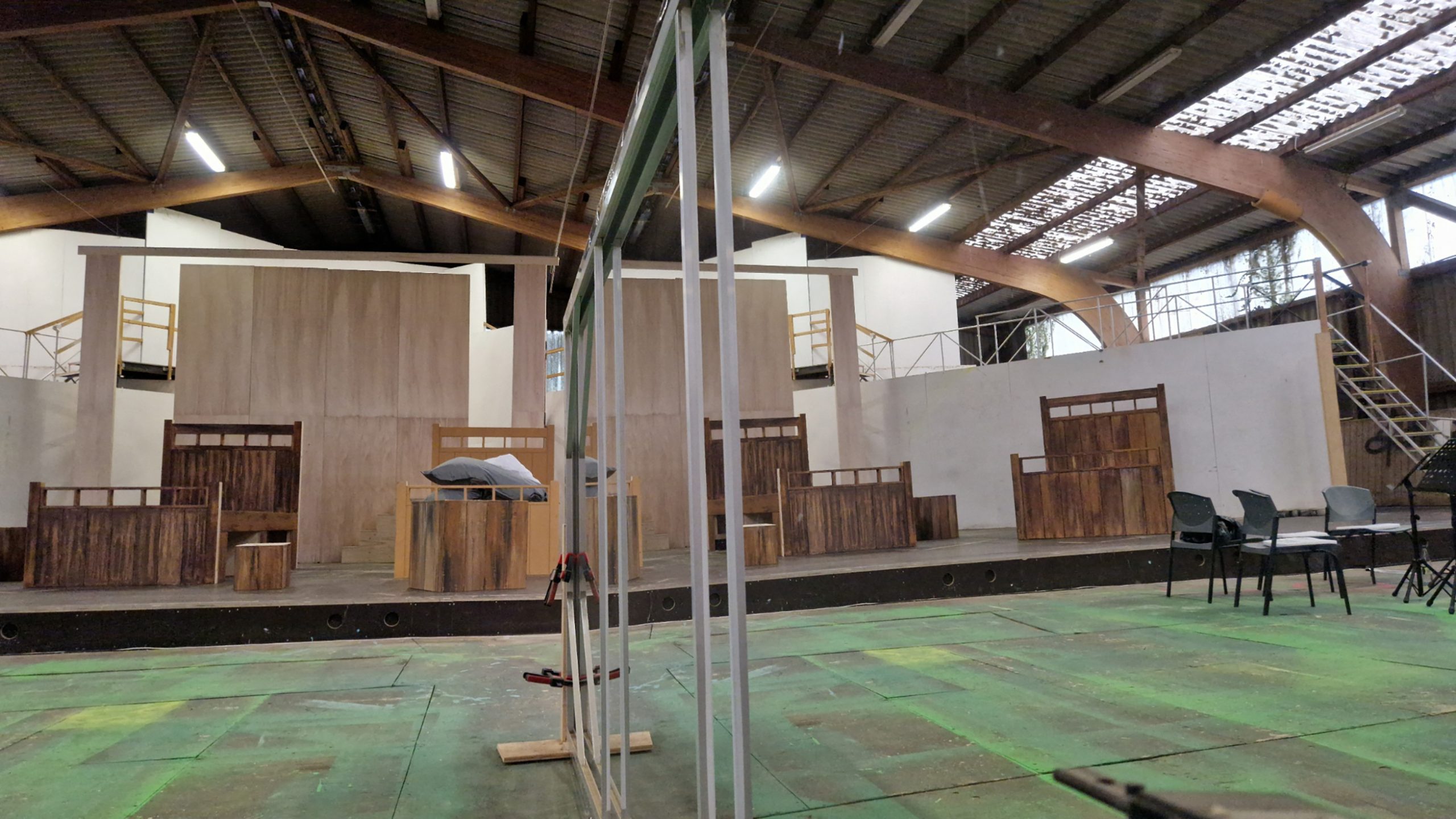 Bühnenaufbau mit mehreren übergroßen Holzbett-Requisiten in einer Werkhalle – gebaut von Extrathings Landscape Studios für ‚Peter Pan‘.